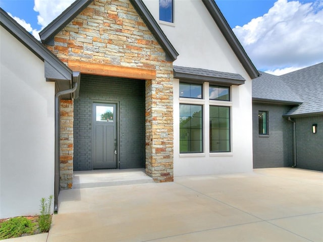 2261 Winter Creek Blvd, Blanchard, OK 73010 - doorway to property with stone siding, stucco siding, a patio, and roof with shingles