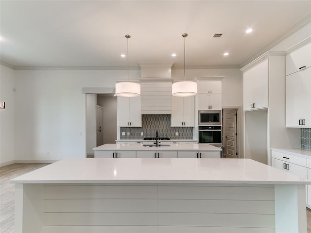 2261 Winter Creek Blvd, Blanchard, OK 73010 - kitchen with oven, a spacious island, stainless steel microwave, tasteful backsplash, and white cabinetry