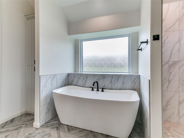2261 Winter Creek Blvd, Blanchard, OK 73010 - bathroom featuring tile walls, a freestanding tub, and a wainscoted wall