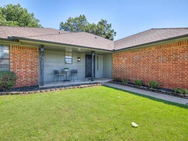 313 Ember Glow Dr, Moore, OK 73160 - property entrance featuring a yard, brick siding, covered porch, and roof with shingles