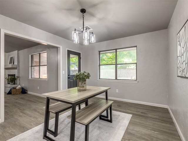 313 Ember Glow Dr, Moore, OK 73160 - dining area featuring wood finished floors, a chandelier, and a large fireplace