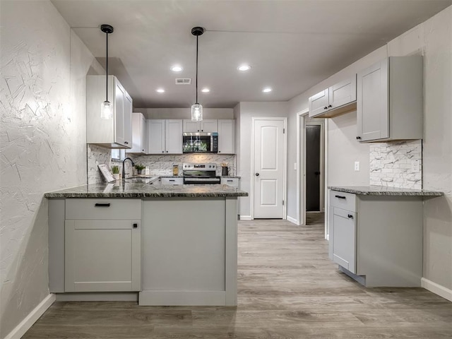 313 Ember Glow Dr, Moore, OK 73160 - kitchen with stainless steel microwave, range with electric stovetop, backsplash, dark stone counters, and a textured wall