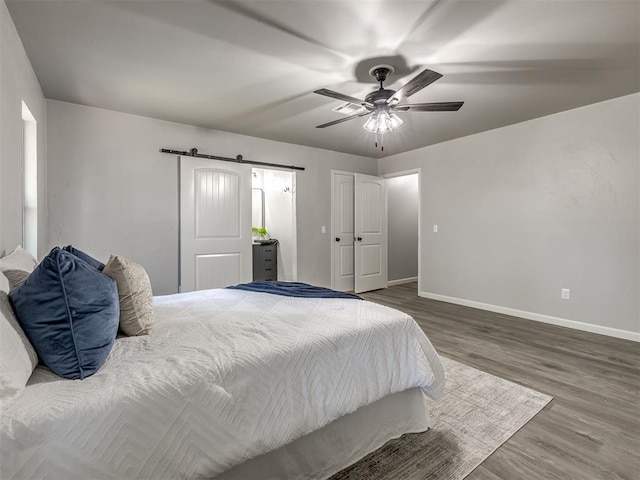 313 Ember Glow Dr, Moore, OK 73160 - bedroom featuring a barn door, wood finished floors, and a ceiling fan