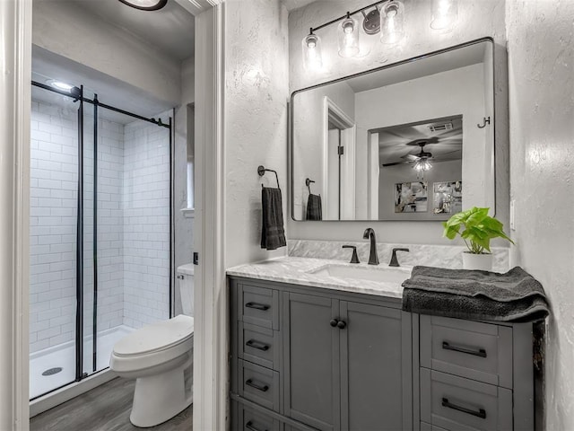 313 Ember Glow Dr, Moore, OK 73160 - bathroom featuring vanity, a textured wall, a stall shower, wood finished floors, and a ceiling fan