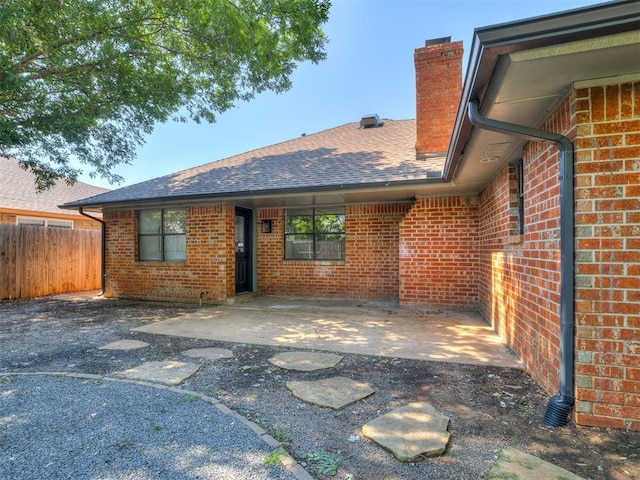 313 Ember Glow Dr, Moore, OK 73160 - back of house with brick siding, a chimney, a shingled roof, and a patio area