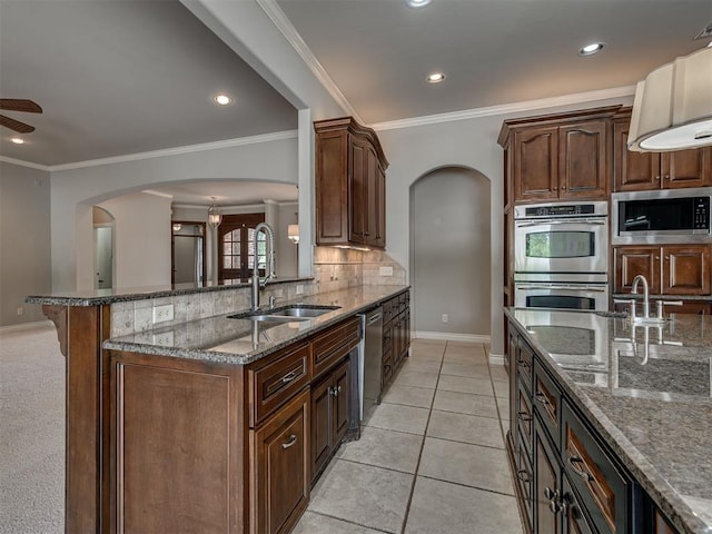 1233 Autumn Creek Dr, Edmond, OK 73003 - kitchen with appliances with stainless steel finishes, arched walkways, dark stone counters, decorative backsplash, and a ceiling fan