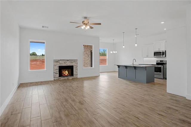2344 Knox Ln, Blanchard, OK 73010 - unfurnished living room featuring ceiling fan, light wood-type flooring, a stone fireplace, and recessed lighting