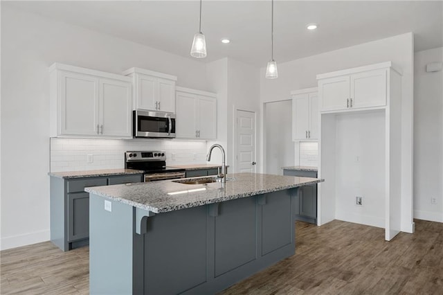 2344 Knox Ln, Blanchard, OK 73010 - kitchen with stainless steel appliances, backsplash, a kitchen island with sink, light stone counters, and light wood-style floors