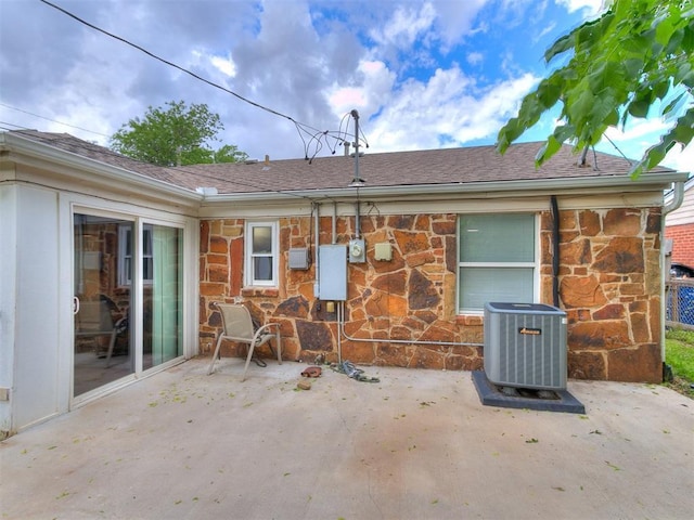 1710 Carlisle Rd, Oklahoma City, OK 73120 - rear view of house featuring stone siding, a patio area, and a shingled roof