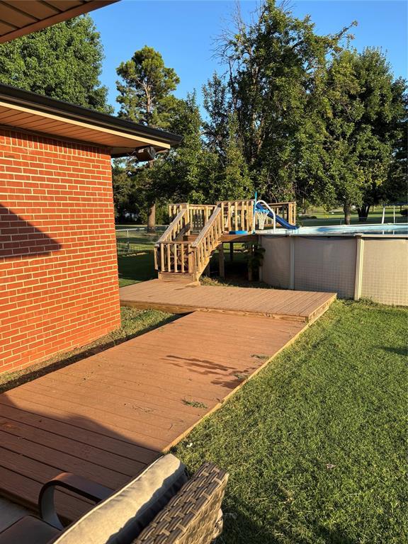 1717 S Webster Dr, Midwest City, OK 73130 - wooden terrace with an outdoor pool and a lawn