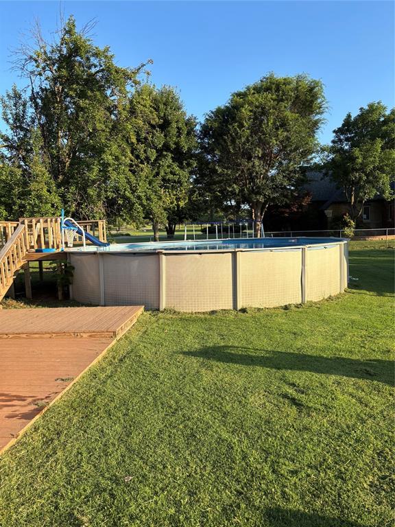 1717 S Webster Dr, Midwest City, OK 73130 - view of green lawn with an outdoor pool and a wooden deck