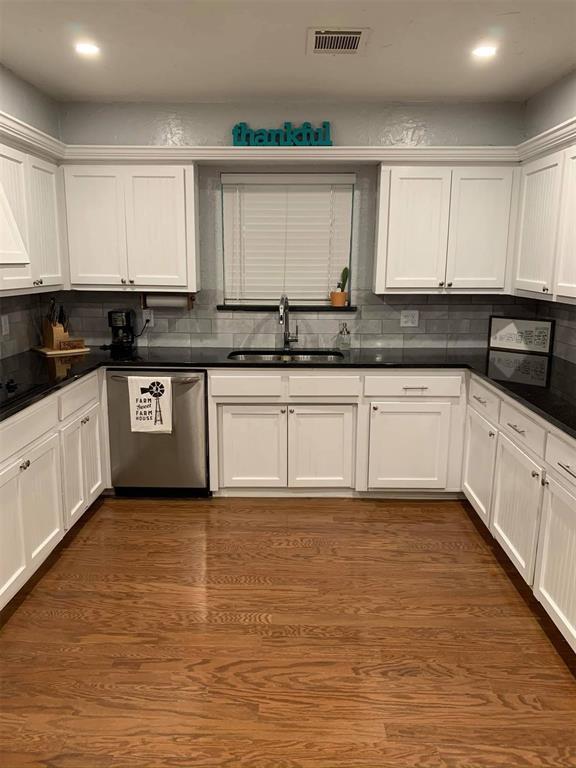 1717 S Webster Dr, Midwest City, OK 73130 - kitchen with stainless steel dishwasher, backsplash, dark countertops, white cabinetry, and recessed lighting