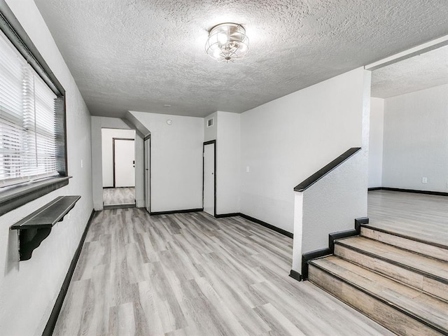 3225 SE 20th St, Oklahoma City, OK 73115 - unfurnished living room with wood finished floors, a textured ceiling, and stairway