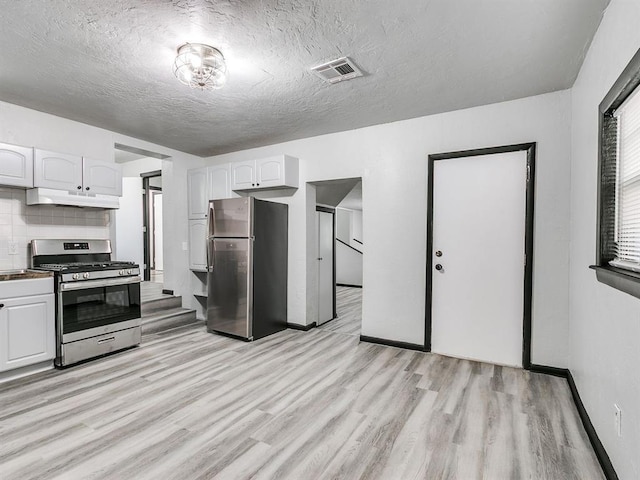 3225 SE 20th St, Oklahoma City, OK 73115 - kitchen featuring stainless steel appliances, under cabinet range hood, white cabinetry, light wood finished floors, and a textured ceiling