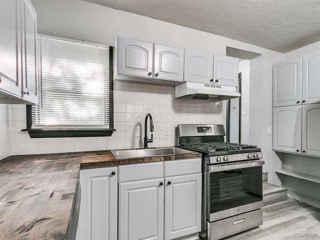 3225 SE 20th St, Oklahoma City, OK 73115 - kitchen featuring stainless steel gas range, under cabinet range hood, light wood-style flooring, dark countertops, and a textured ceiling