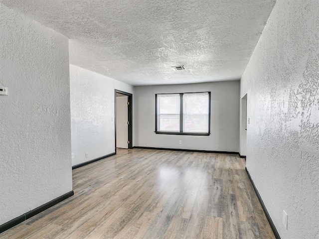 3225 SE 20th St, Oklahoma City, OK 73115 - empty room with a textured wall, wood finished floors, and a textured ceiling