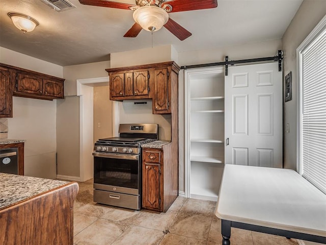 201 N Base Ave, Norman, OK 73069 - kitchen featuring stainless steel gas range, ceiling fan, a barn door, light tile patterned flooring, and light stone countertops