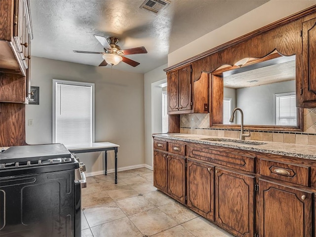 201 N Base Ave, Norman, OK 73069 - kitchen with black range with gas cooktop, decorative backsplash, a ceiling fan, light countertops, and brown cabinetry