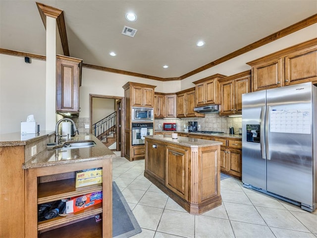 1621 NW 182nd St, Edmond, OK 73012 - kitchen featuring stainless steel appliances, brown cabinets, crown molding, tasteful backsplash, and under cabinet range hood
