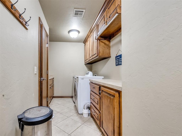 1621 NW 182nd St, Edmond, OK 73012 - laundry area featuring washing machine and clothes dryer, cabinet space, light tile patterned flooring, and a textured wall