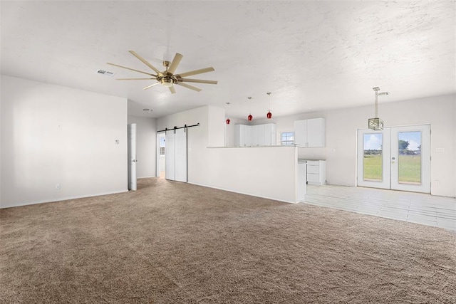 27919 Tortola Ln, Blanchard, OK 73010 - unfurnished living room with a barn door, light carpet, a ceiling fan, and french doors