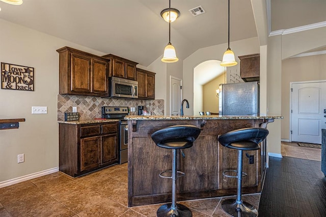 1613 NW 124th St, Oklahoma City, OK 73120 - kitchen with appliances with stainless steel finishes, a breakfast bar, tasteful backsplash, dark brown cabinets, and lofted ceiling