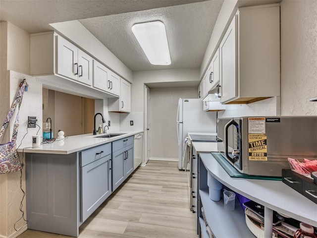 14313 N Pennsylvania Ave Unit 7E, Oklahoma City, OK 73134 - kitchen with light wood-type flooring, dishwasher, light countertops, gray cabinets, and a textured ceiling