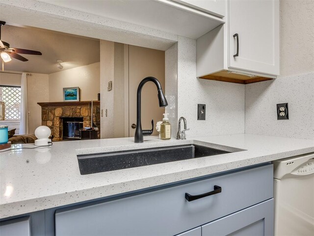 14313 N Pennsylvania Ave Unit 7E, Oklahoma City, OK 73134 - kitchen with white dishwasher, ceiling fan, light stone countertops, and a fireplace
