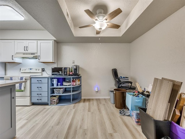 14313 N Pennsylvania Ave Unit 7E, Oklahoma City, OK 73134 - kitchen with white electric range, a tray ceiling, under cabinet range hood, light wood-style floors, and light countertops