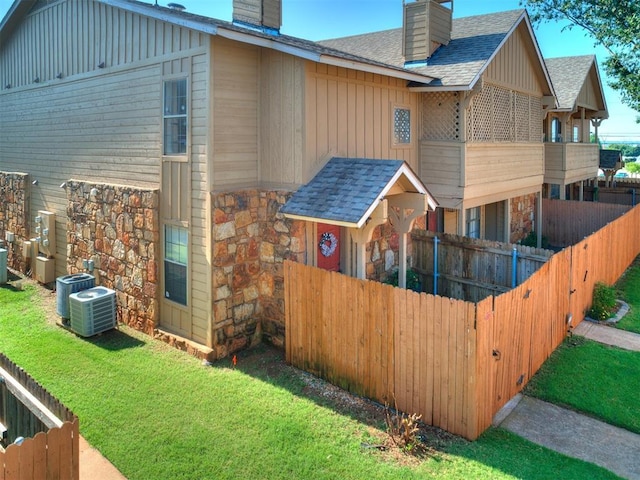14313 N Pennsylvania Ave Unit 7E, Oklahoma City, OK 73134 - view of property exterior featuring a chimney, board and batten siding, stone siding, and a shingled roof