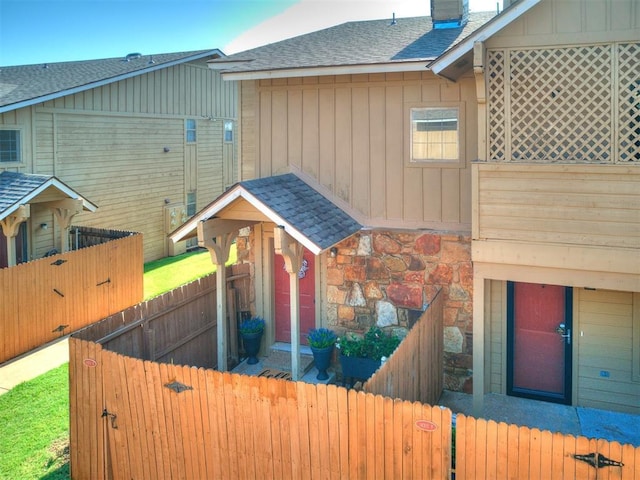 14313 N Pennsylvania Ave Unit 7E, Oklahoma City, OK 73134 - view of front of home with a shingled roof, a gate, board and batten siding, a chimney, and stone siding
