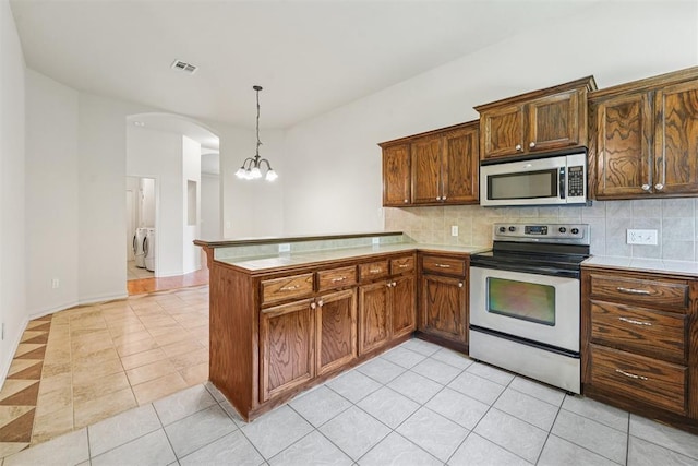 9716 SW 21st Ter, Oklahoma City, OK 73128 - kitchen with appliances with stainless steel finishes, washer and clothes dryer, light tile patterned flooring, and backsplash