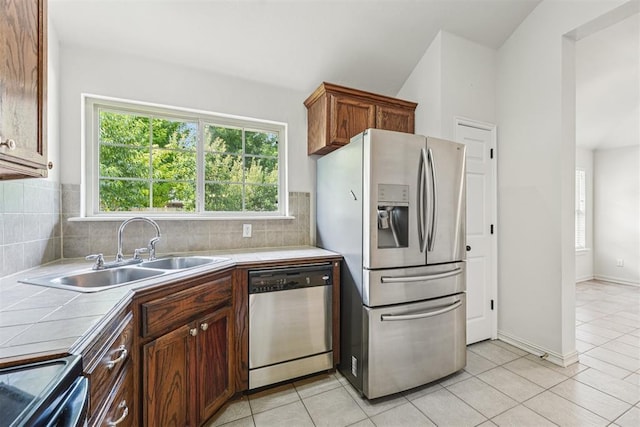 9716 SW 21st Ter, Oklahoma City, OK 73128 - kitchen featuring appliances with stainless steel finishes, tile counters, tasteful backsplash, light tile patterned flooring, and lofted ceiling