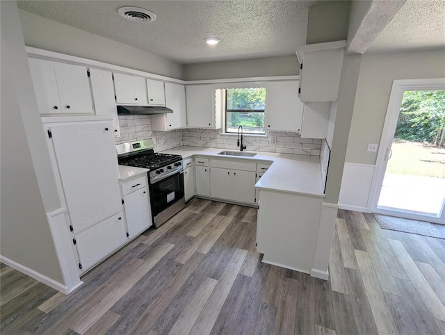 104 SW 10th St, Moore, OK 73160 - kitchen with gas stove, under cabinet range hood, a textured ceiling, light countertops, and healthy amount of natural light