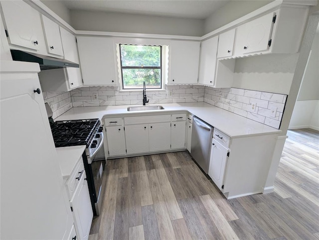 104 SW 10th St, Moore, OK 73160 - kitchen featuring under cabinet range hood, stainless steel appliances, light wood finished floors, decorative backsplash, and white cabinetry
