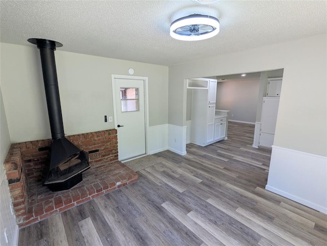 104 SW 10th St, Moore, OK 73160 - unfurnished living room featuring wainscoting, wood finished floors, a textured ceiling, and a wood stove