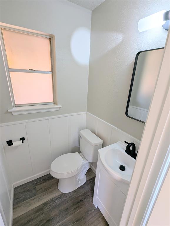 104 SW 10th St, Moore, OK 73160 - half bath featuring vanity, a wainscoted wall, wood finished floors, and a decorative wall
