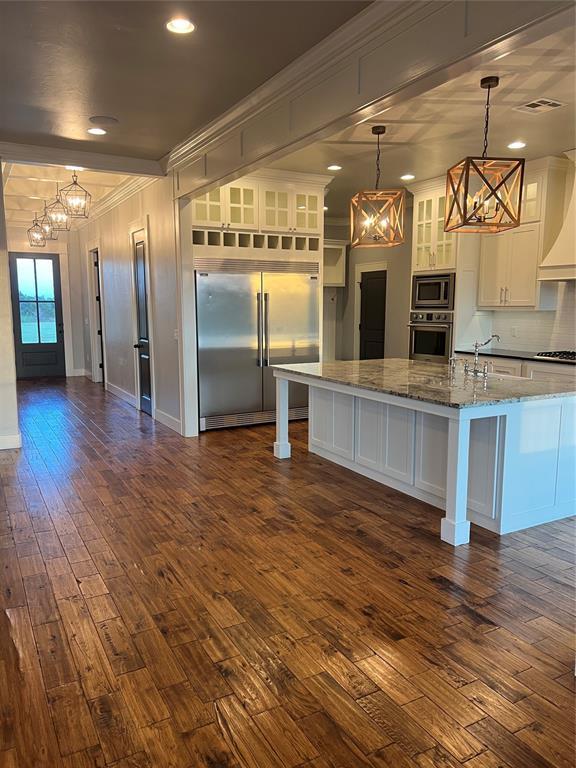 17566 N County Road 3190, Pauls Valley, OK 73075 - kitchen with built in appliances, a chandelier, white cabinets, dark wood finished floors, and light stone countertops