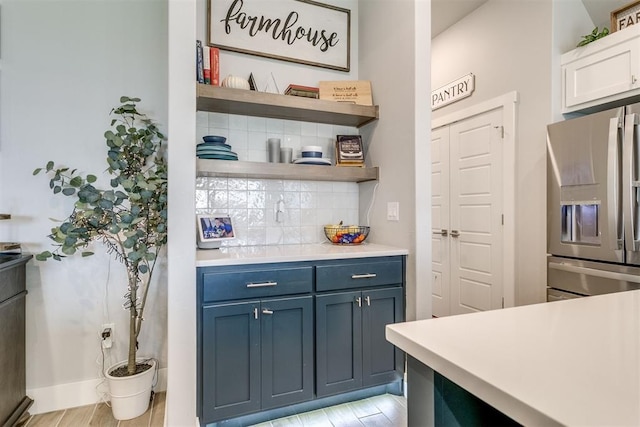 10125 NW 99th St, Yukon, OK 73099 - kitchen with stainless steel fridge, tasteful backsplash, light countertops, open shelves, and blue cabinetry