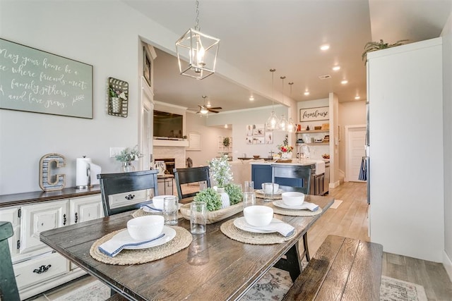 10125 NW 99th St, Yukon, OK 73099 - dining area with a ceiling fan, light wood-style floors, a chandelier, a fireplace, and recessed lighting