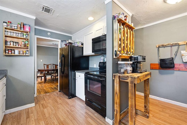 807 Thompson Dr, El Reno, OK 73036 - kitchen with black appliances, white cabinets, light wood-style flooring, ornamental molding, and dark countertops