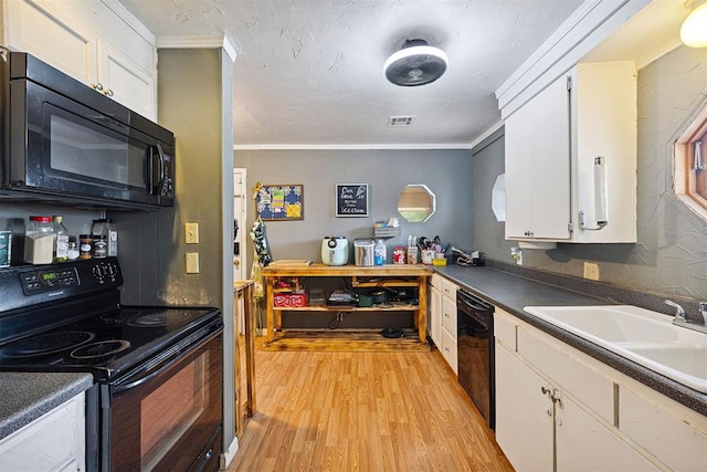 807 Thompson Dr, El Reno, OK 73036 - kitchen with black appliances, light wood-style flooring, white cabinets, crown molding, and dark countertops