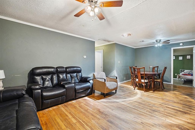 807 Thompson Dr, El Reno, OK 73036 - living room featuring ceiling fan, a textured ceiling, light wood-style floors, and crown molding