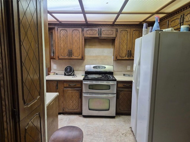 4300 N Butler Pl, Oklahoma City, OK 73118 - kitchen with white refrigerator with ice dispenser, range with two ovens, light countertops, and brown cabinets