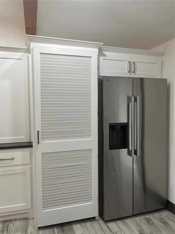 2416 S Shartel Ave, Oklahoma City, OK 73109 - kitchen view of stainless steel fridge with ice dispenser, white cabinetry, and light wood finished floors