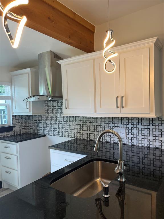2416 S Shartel Ave, Oklahoma City, OK 73109 - kitchen featuring wall chimney exhaust hood, dark stone countertops, white cabinets, and decorative backsplash
