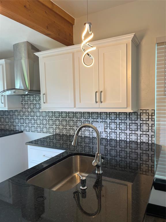 2416 S Shartel Ave, Oklahoma City, OK 73109 - kitchen featuring wall chimney range hood, dark stone countertops, white cabinetry, tasteful backsplash, and pendant lighting