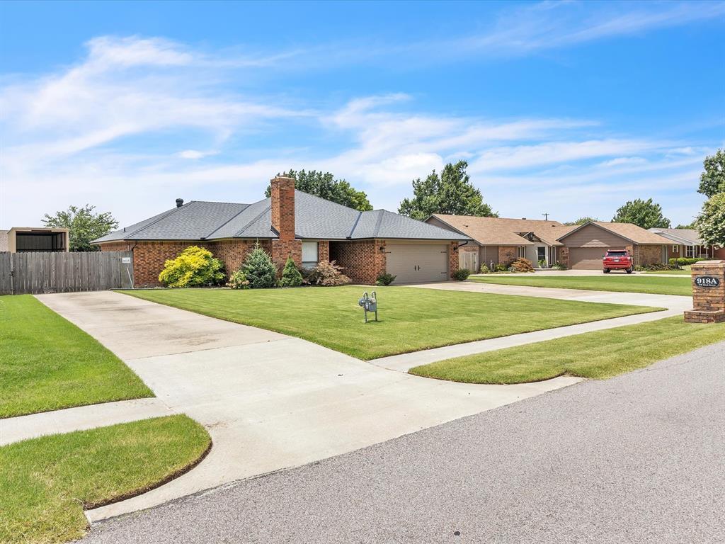 918 NW 32nd St Unit A, Oklahoma City, OK 73160 - view of front facade featuring concrete driveway, brick siding, an attached garage, a residential view, and a chimney