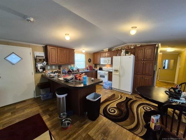 2908 Harber Loop Dr, Grove, OK 74344 - kitchen with white appliances, wood finished floors, dark countertops, vaulted ceiling, and brown cabinetry