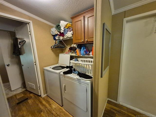 2908 Harber Loop Dr, Grove, OK 74344 - washroom featuring independent washer and dryer, cabinet space, dark wood-style flooring, ornamental molding, and a textured ceiling